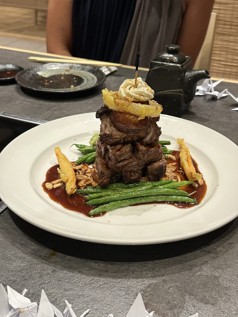 A beautifully plated short rib dish at Hanagi — stacked tall with green beans, crispy garnish, and rich brown sauce