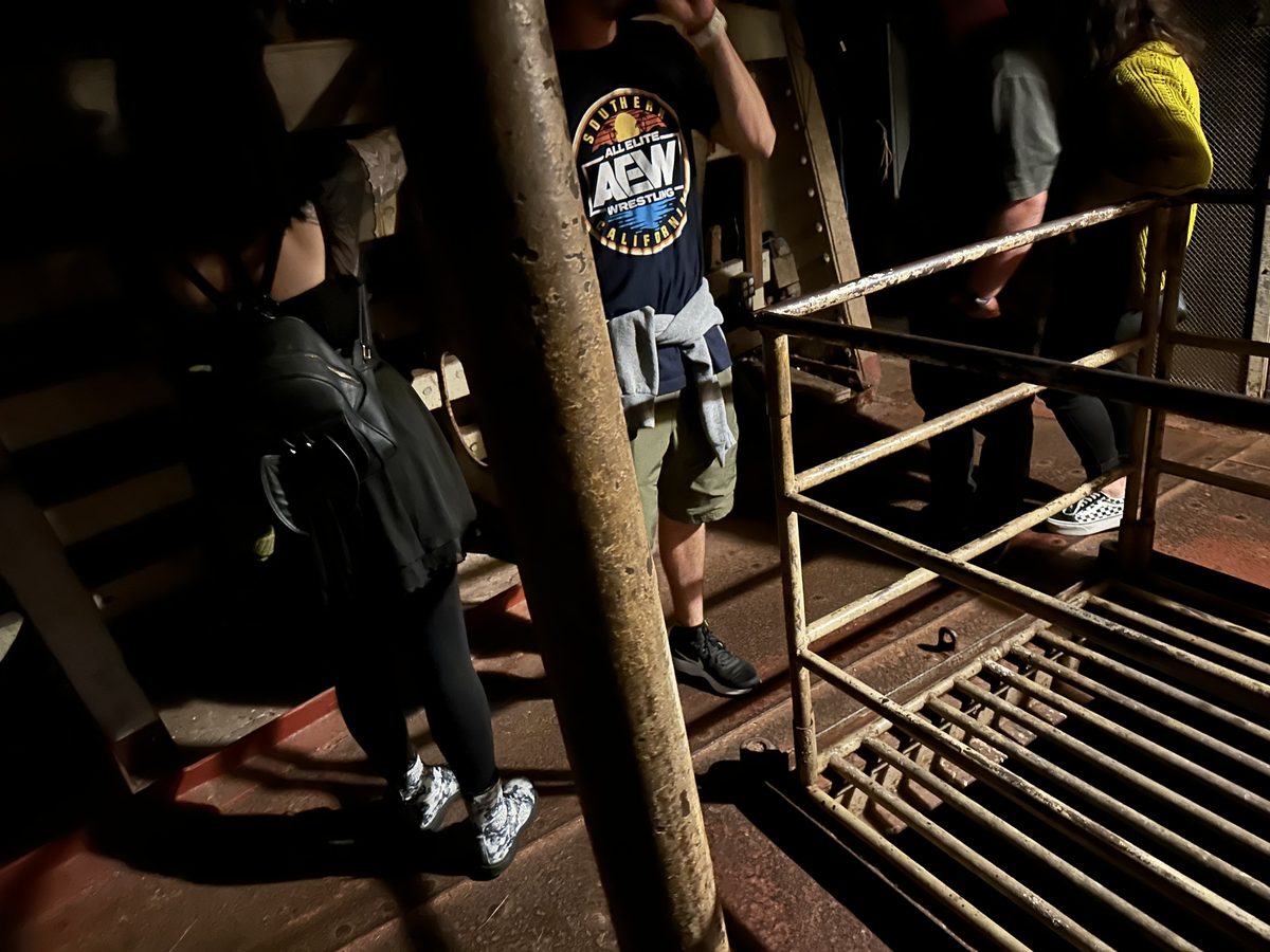 Visitors descending steep rusted ship stairs during a below-decks tour on the Queen Mary