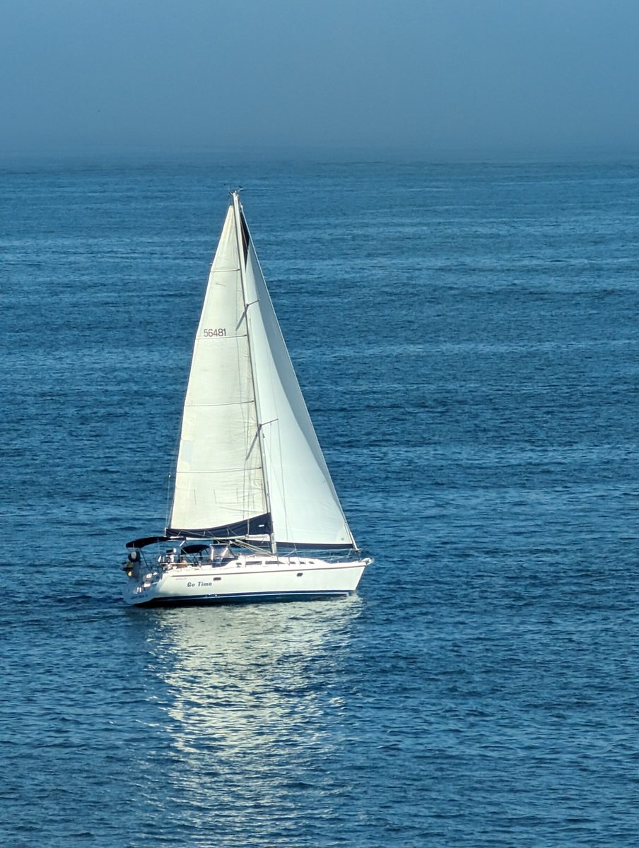 A sailboat on calm blue Pacific water, viewed from the Queen Mary's upper deck