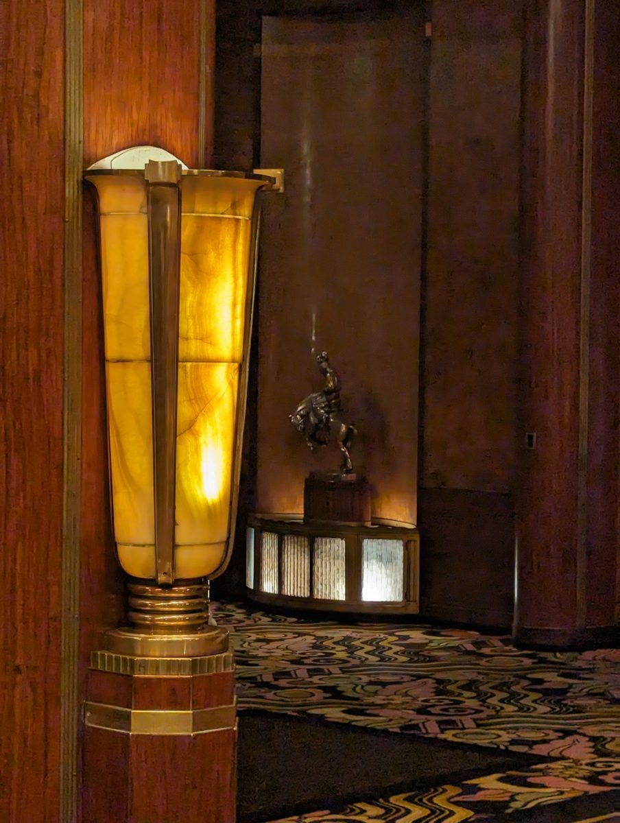 An original amber alabaster torch lamp with a brass base, with a bronze equestrian statue visible in the background