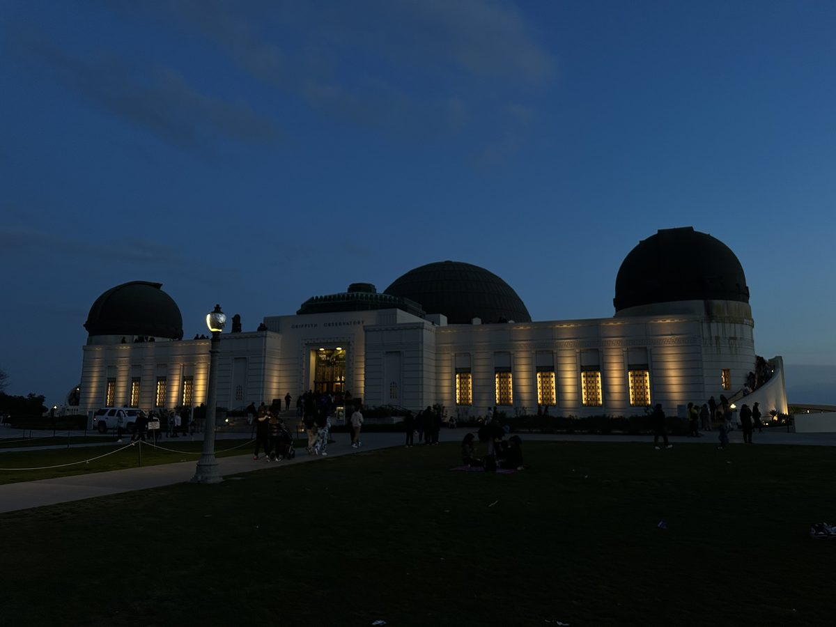 A darker view of the Griffith Observatory domes and lit facade at night from a different angle