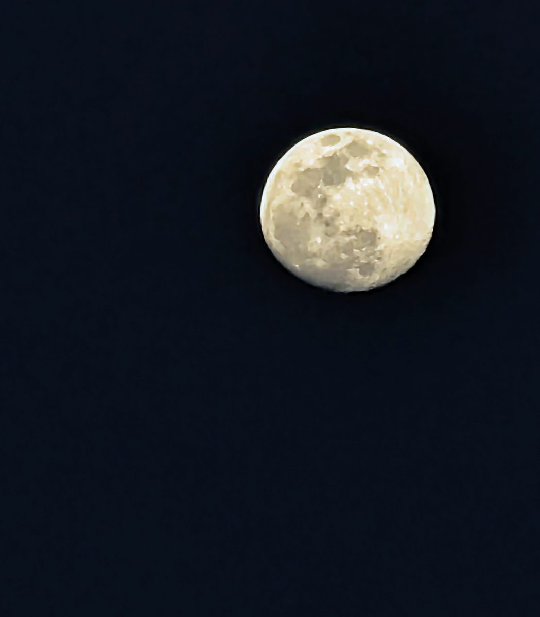 A close telephoto shot of a bright full moon against a dark night sky