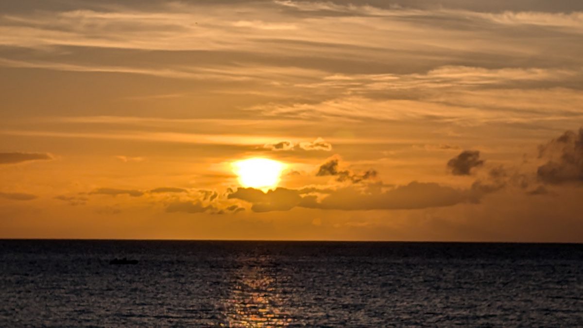 The Ka'anapali sun burning gold behind clouds as it sinks into the Pacific