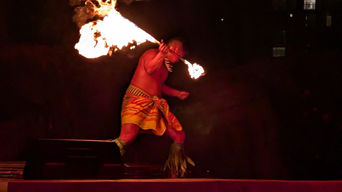 Long exposure of the fire knife dancer spinning and fire-breathing — fire arcing in a blur