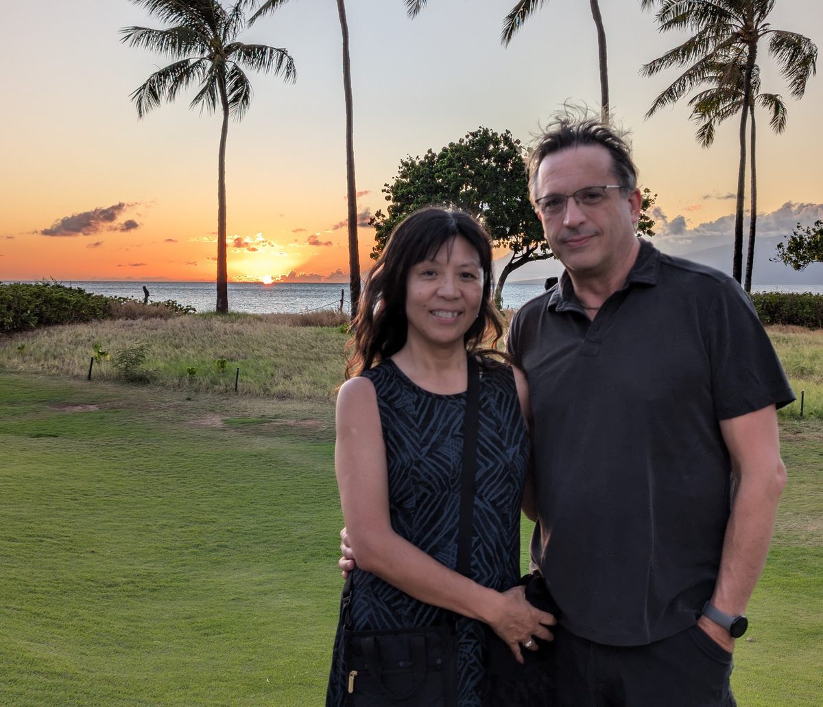 Ako and Eddy together at the final Ka'anapali sunset — palm trees silhouetted against an orange sky