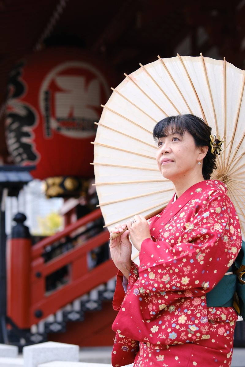 Ako alone with wagasa, red Sensoji lanterns and signage visible behind her