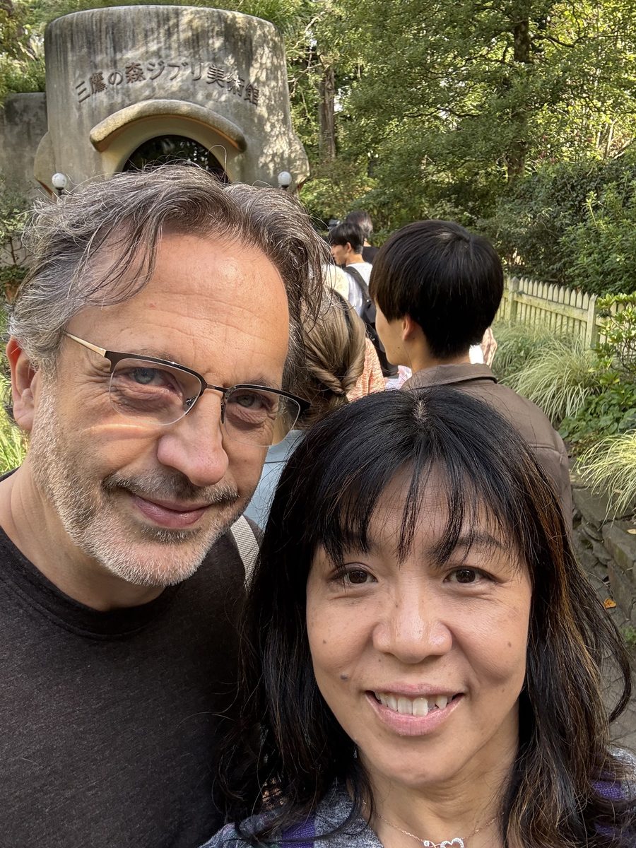 Eddy and Ako selfie in front of the stone Ghibli Museum entrance marker among trees