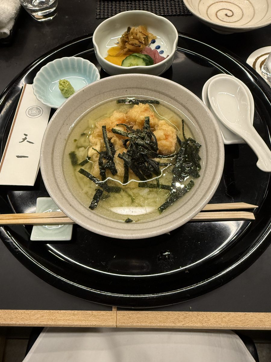 A bowl of tempura and shredded nori in a light ankake broth with wasabi on the side