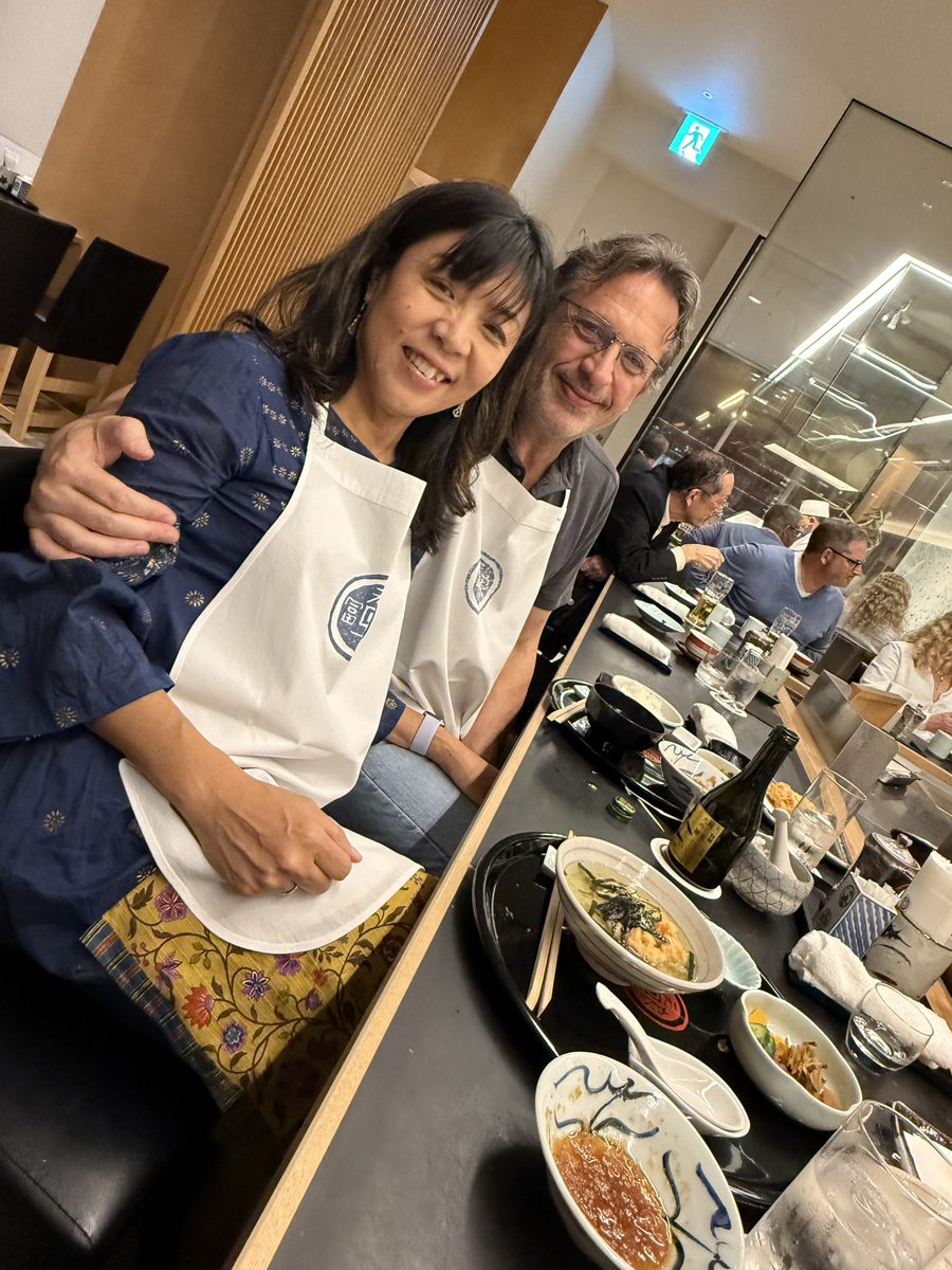 Eddy and Ako in white aprons, arms around each other, smiling at the Tenichi counter