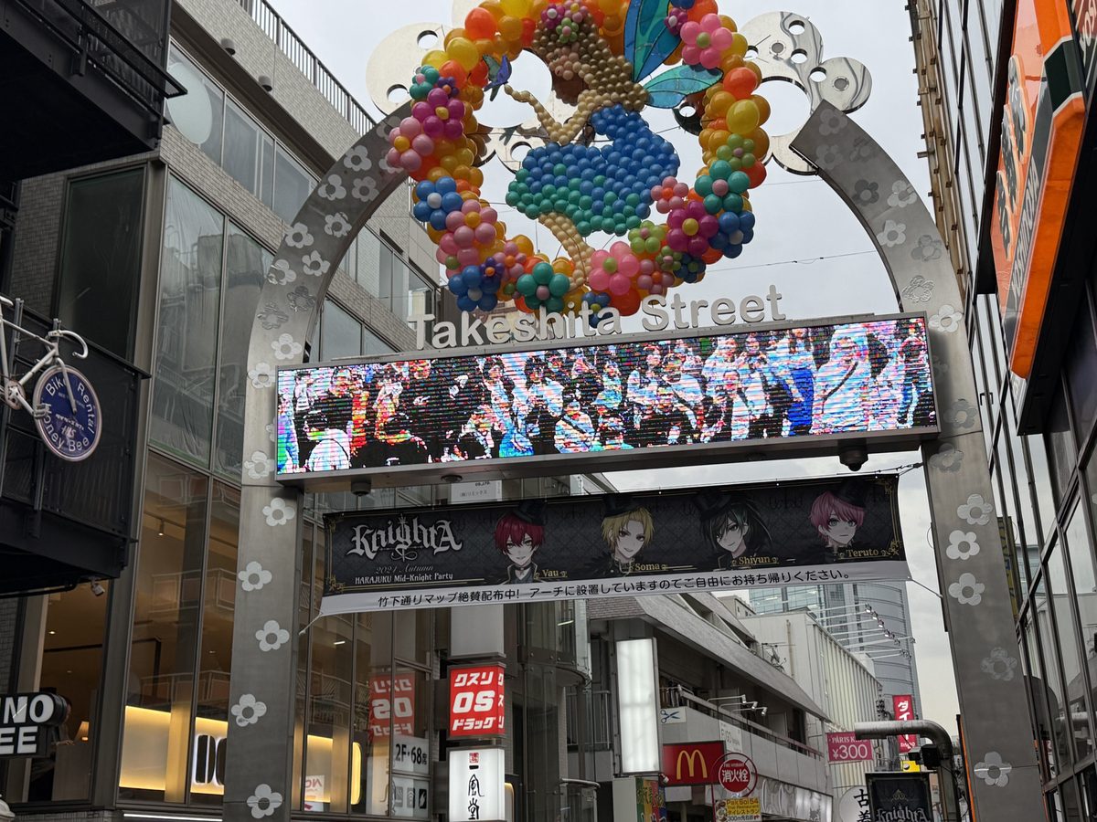 The ornate Takeshita Street entrance arch with balloon flowers and a digital sign