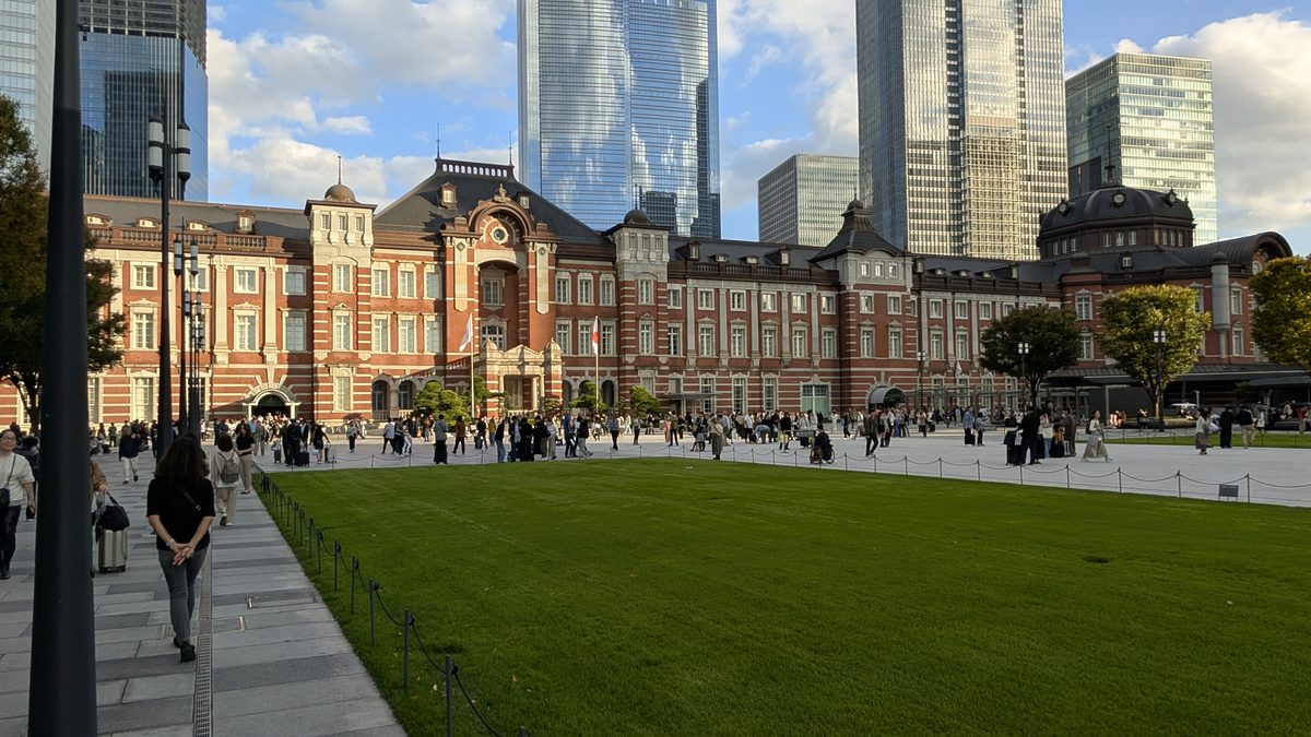 The red-brick Marunouchi facade of Tokyo Station with the plaza lawn