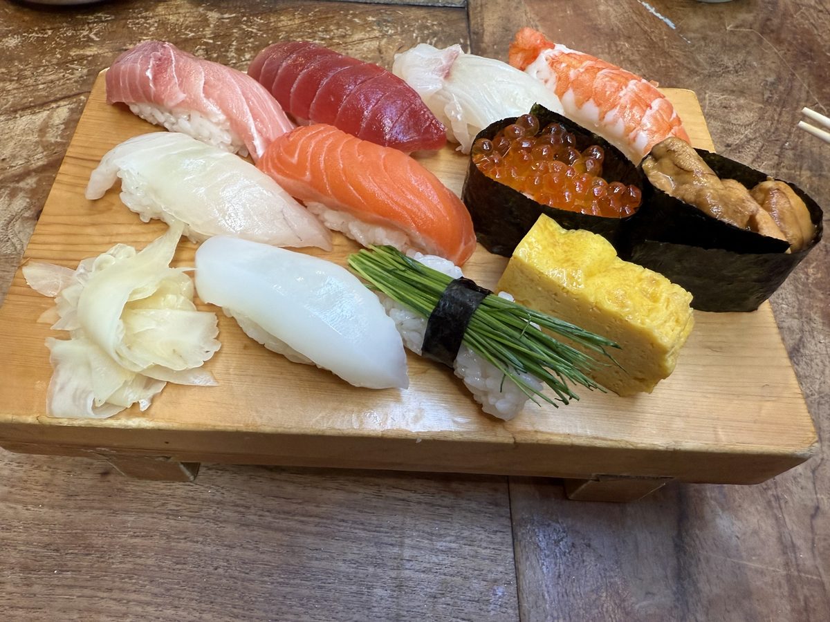 A wooden board of assorted nigiri sushi with pickled ginger