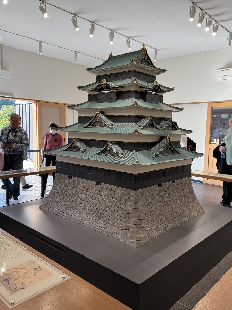 A large detailed scale model of a Japanese castle keep with green roofs