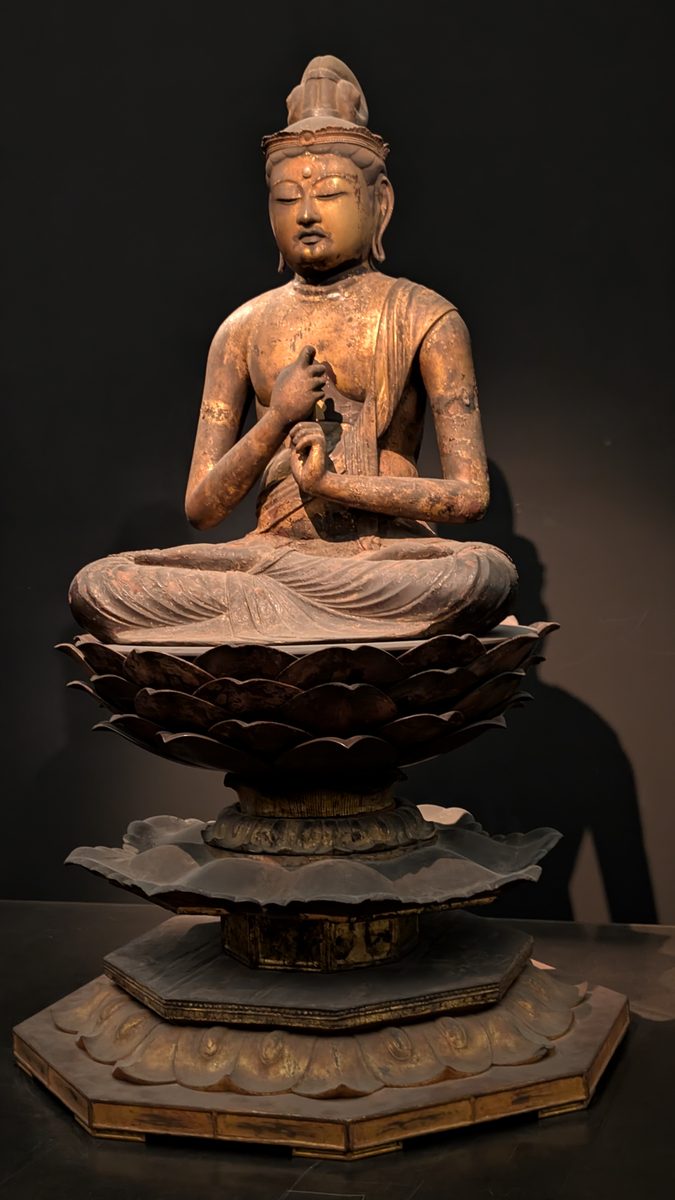 A seated wooden Buddha on an elaborate carved lotus throne