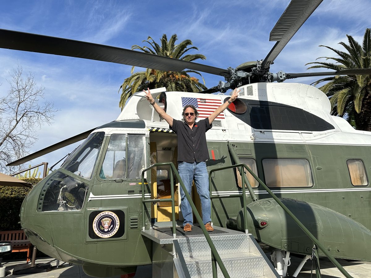 Eddy in the doorway of the presidential helicopter with his arms raised — the Nixon Library 2023