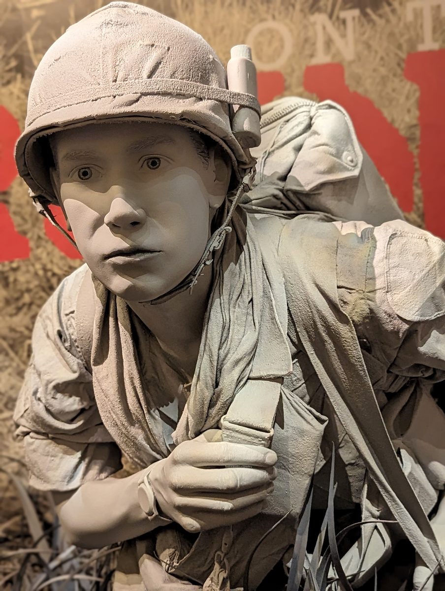 Another grey life-size sculpture of a Vietnam War soldier frozen mid-advance