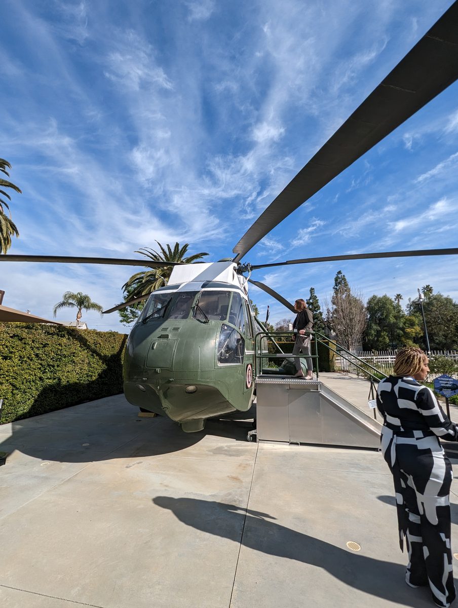 The green-and-white presidential Sea King helicopter on display outdoors with boarding stairs under a blue sky