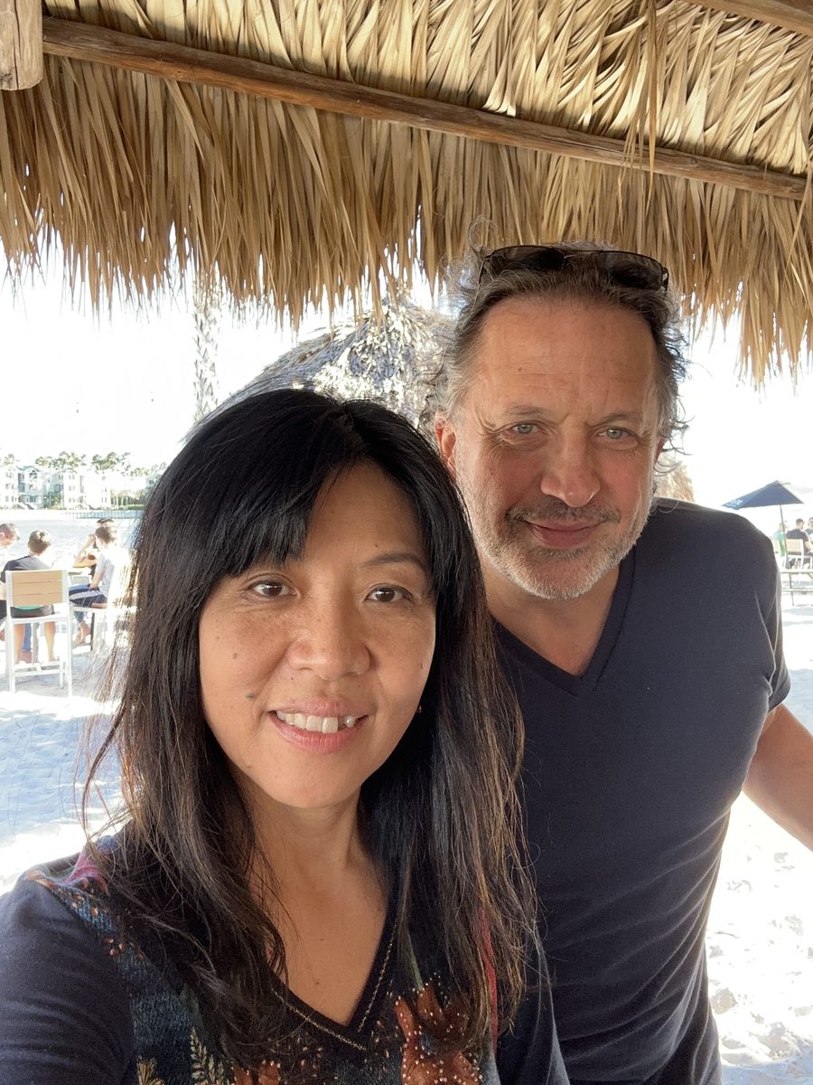 Eddy and Ako selfie under a thatched tiki roof by the water