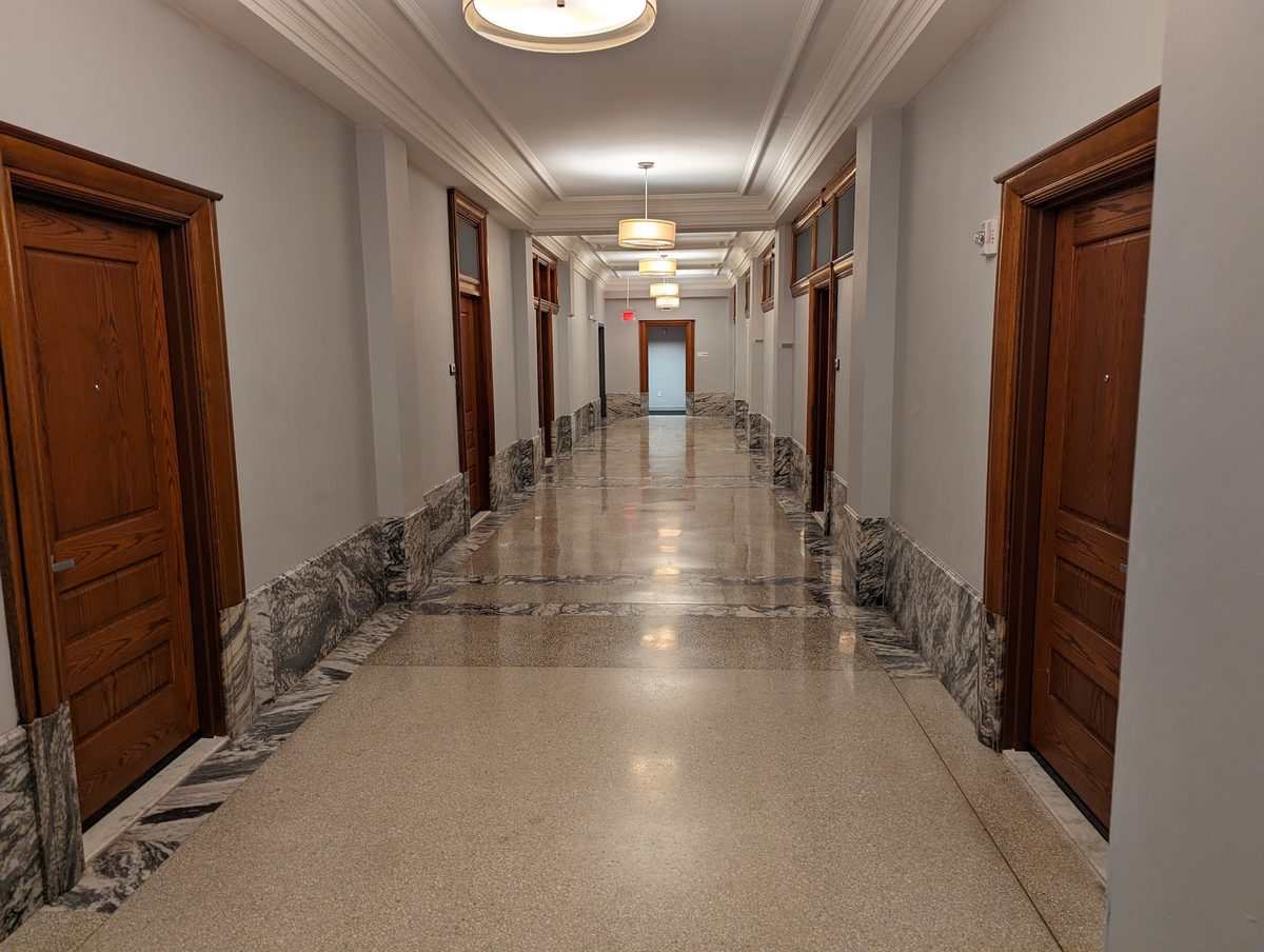 An elegant marble-lined interior corridor with wood doors and pendant lights