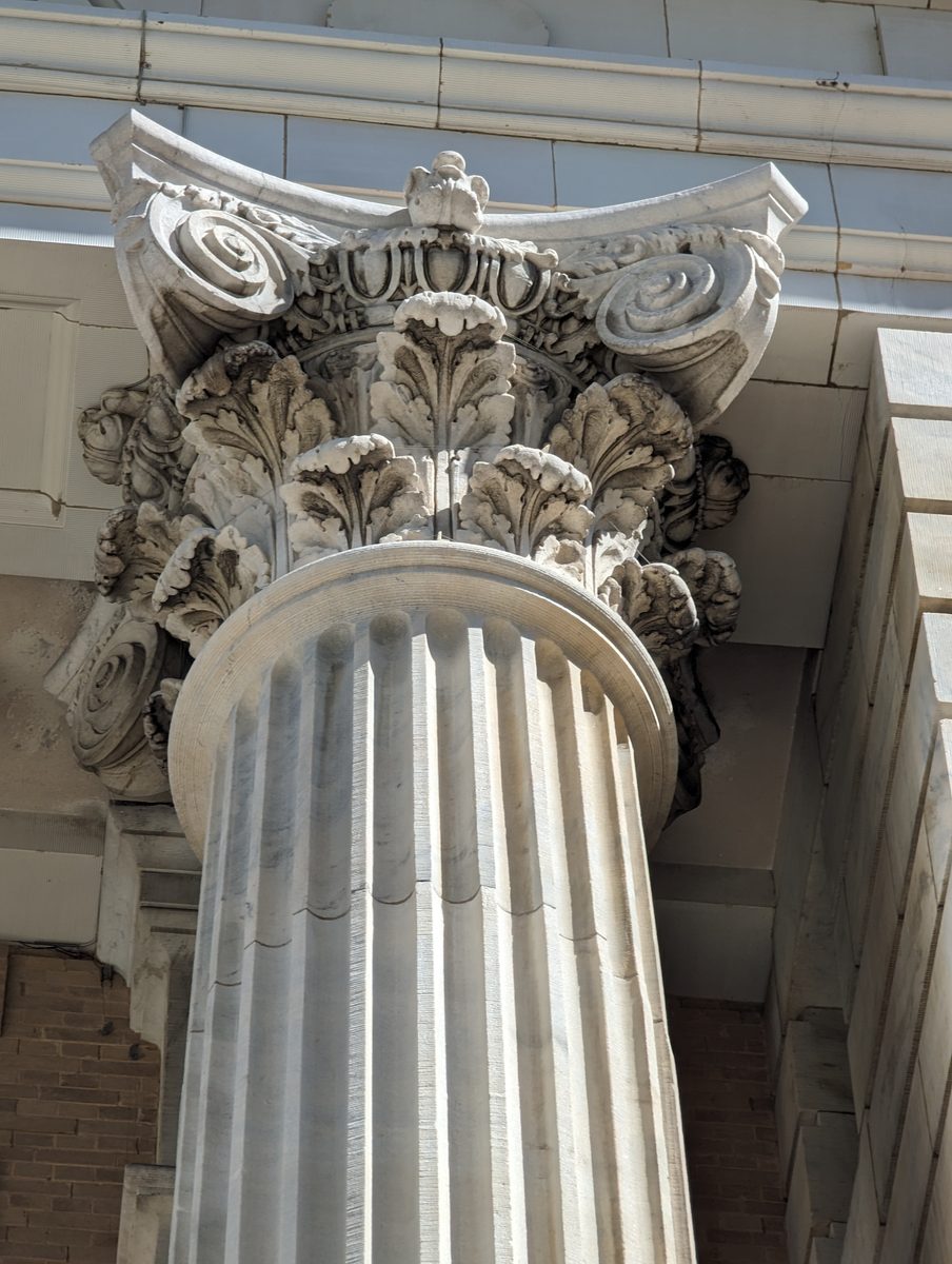 A carved Corinthian column capital with acanthus leaves against the sky