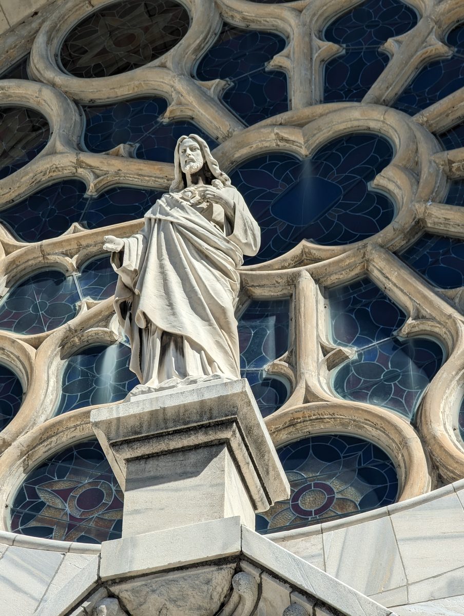 The Sacred Heart statue set into the church's stone tracery below the rose window