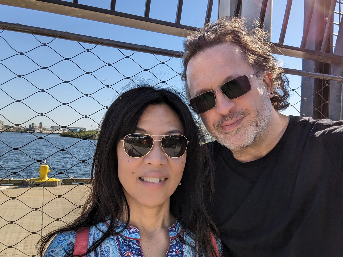Eddy and Ako selfie on the Tampa Riverwalk, bright water behind them